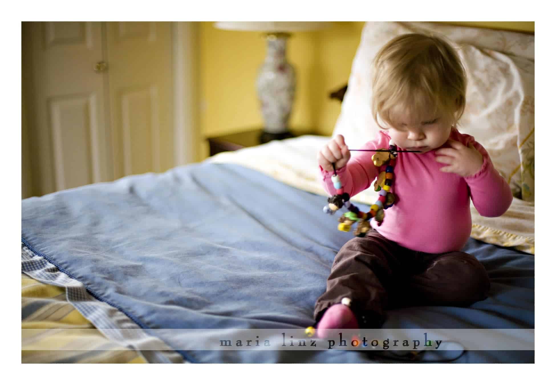 Playing with necklaces on Grammie's bed